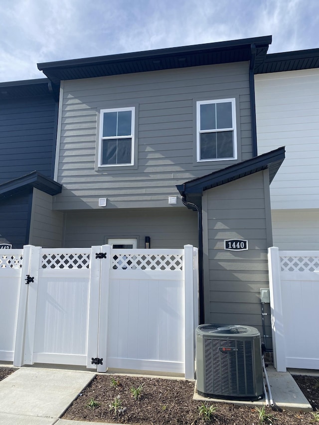 view of front facade featuring a gate, cooling unit, fence, and a garage