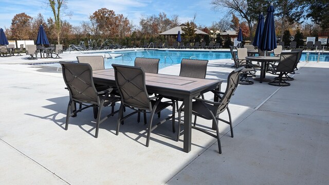 community pool with fence, outdoor dining space, and a patio