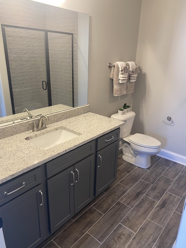full bathroom with wood tiled floors, a shower stall, vanity, toilet, and baseboards
