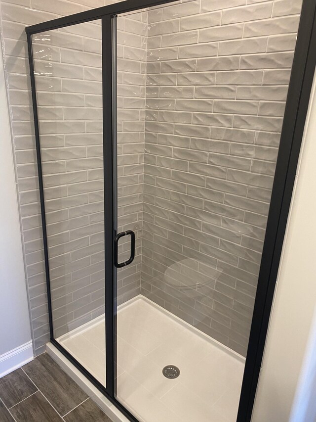 bathroom featuring a stall shower, wood finished floors, and baseboards