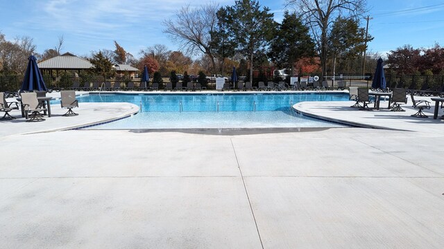 community pool with fence and a patio area