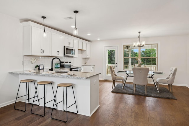 1543 Fredrick Dr, Clarksville, TN 37042 - kitchen featuring appliances with stainless steel finishes, a peninsula, white cabinetry, decorative backsplash, and a chandelier