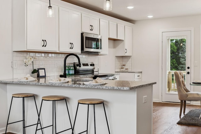 1543 Fredrick Dr, Clarksville, TN 37042 - kitchen with stainless steel appliances, a peninsula, white cabinets, decorative backsplash, and wood finished floors