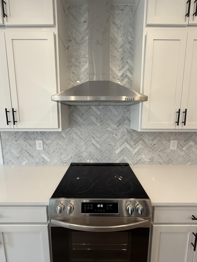 kitchen featuring stainless steel electric range oven, wall chimney exhaust hood, light countertops, and backsplash