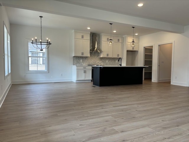 kitchen with wall chimney exhaust hood, open floor plan, a chandelier, baseboards, and recessed lighting