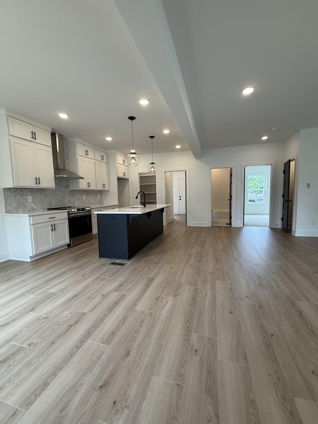 kitchen with electric range, wall chimney exhaust hood, open floor plan, light countertops, and decorative backsplash