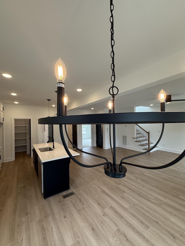 detailed view of a sink, wood finished floors, recessed lighting, and baseboards