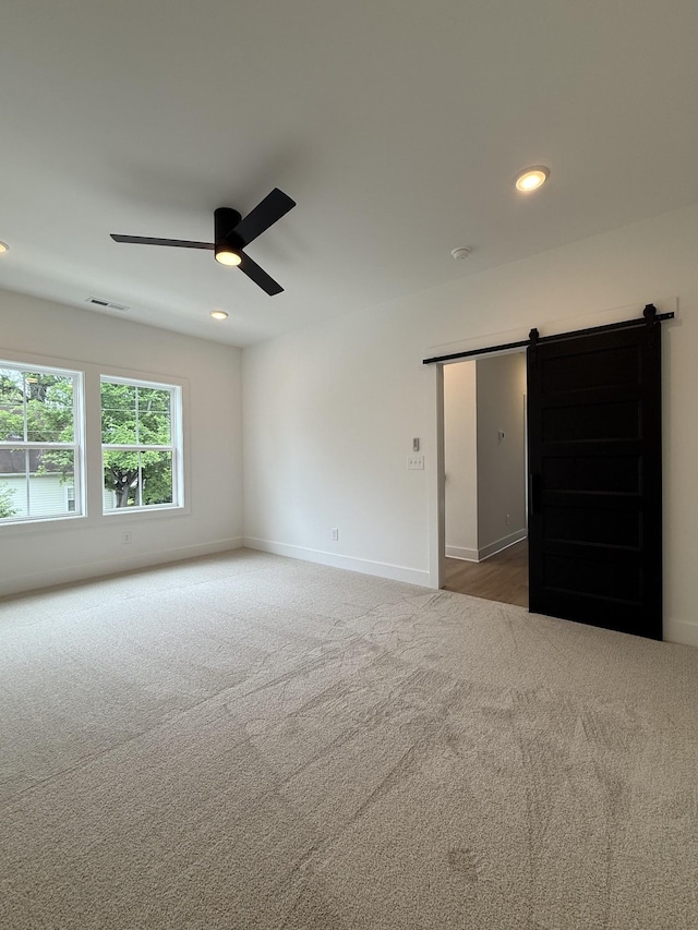 spare room with a barn door, carpet flooring, ceiling fan, baseboards, and recessed lighting
