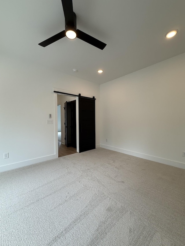 spare room with carpet flooring, baseboards, a ceiling fan, recessed lighting, and a barn door