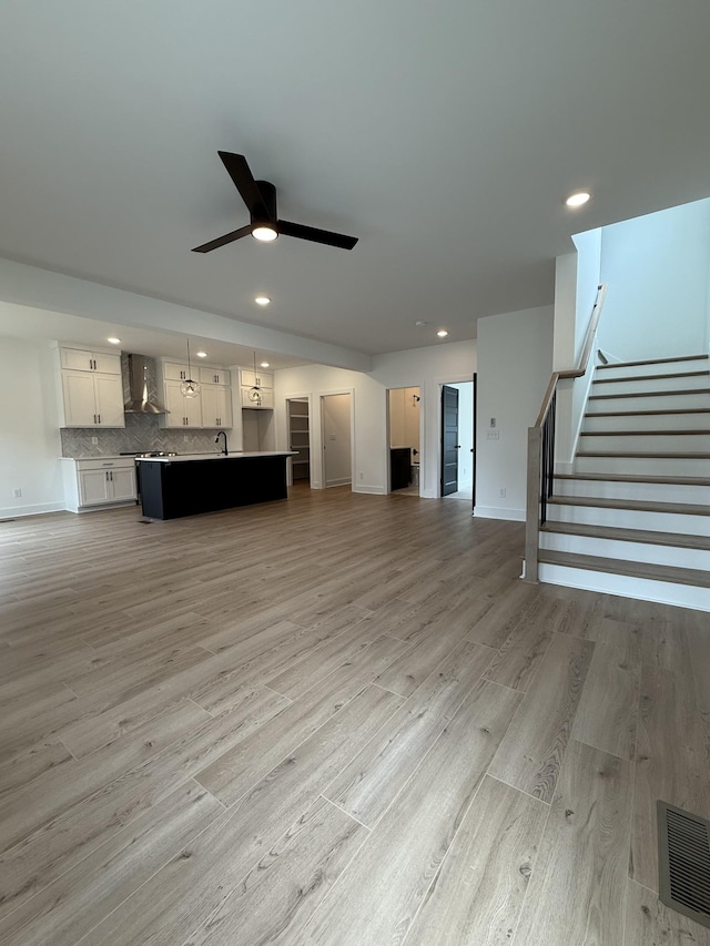 unfurnished living room featuring recessed lighting, ceiling fan, stairway, light wood finished floors, and baseboards