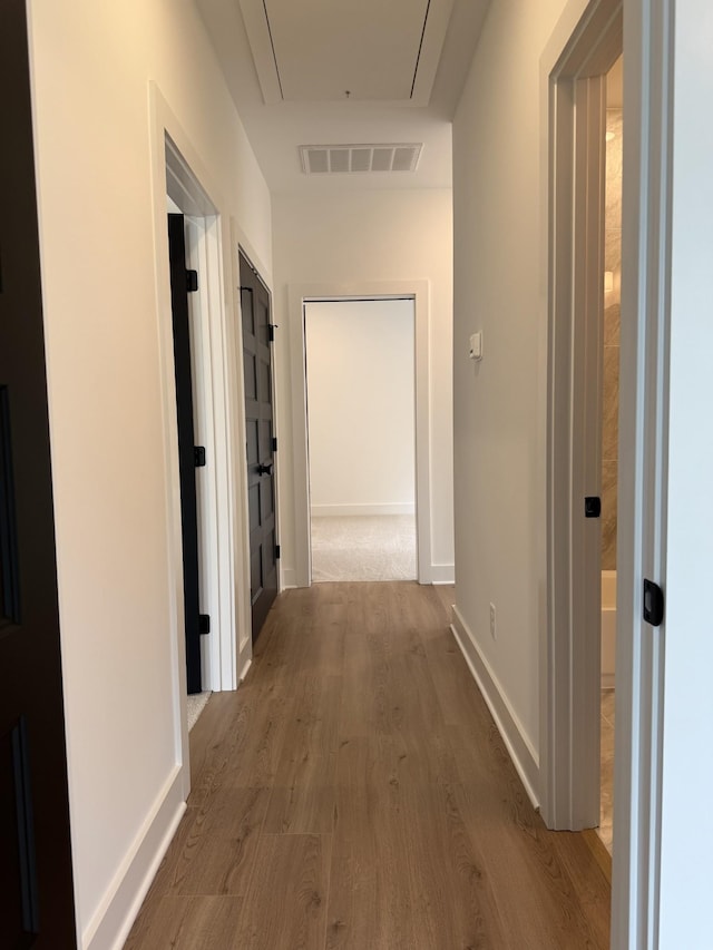 hall with attic access, wood finished floors, and baseboards