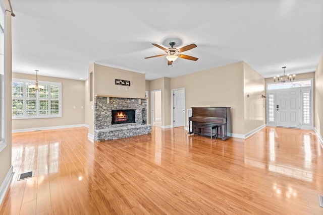 3337 Tarsus Rd, Palmyra, TN 37142 - unfurnished living room with a chandelier, ceiling fan, light wood-style floors, and a stone fireplace