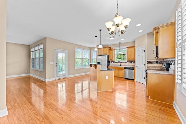 3337 Tarsus Rd, Palmyra, TN 37142 - kitchen featuring stainless steel appliances, backsplash, light wood finished floors, a kitchen bar, and a chandelier