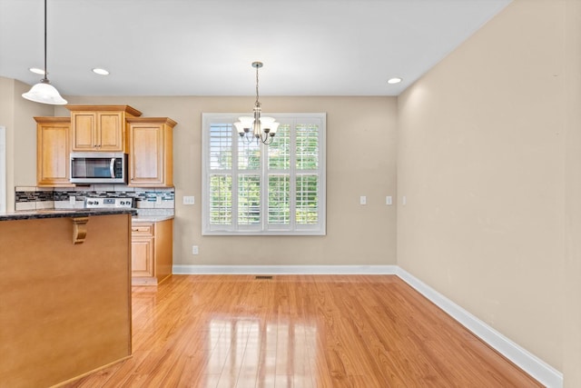 3337 Tarsus Rd, Palmyra, TN 37142 - kitchen featuring stainless steel microwave, light wood-type flooring, backsplash, a chandelier, and hanging light fixtures