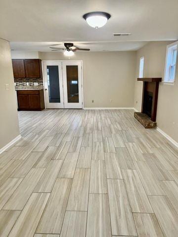unfurnished living room with light wood finished floors, baseboards, a fireplace, and ceiling fan