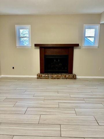 detailed view of a fireplace with raised hearth, wood finish floors, and baseboards