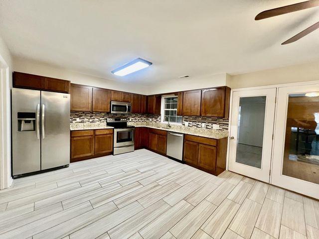 kitchen featuring appliances with stainless steel finishes, a sink, backsplash, and ceiling fan