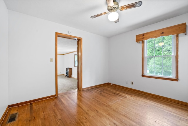 empty room featuring light wood-type flooring, baseboards, and ceiling fan