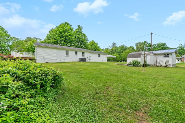 view of green lawn featuring an outbuilding, a storage unit, and cooling unit