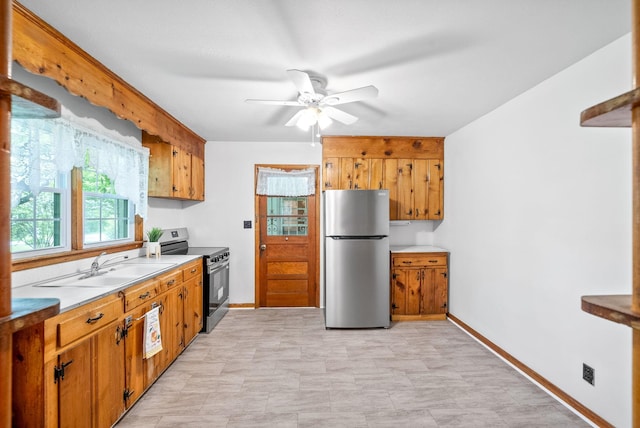 kitchen with appliances with stainless steel finishes, ceiling fan, brown cabinetry, and a sink