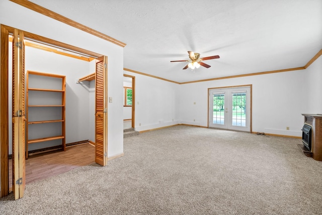 unfurnished living room with carpet flooring, ceiling fan, baseboards, ornamental molding, and french doors