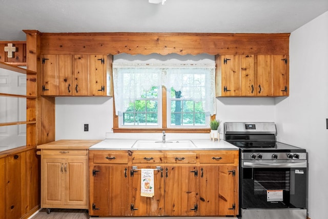 kitchen with stainless steel range with electric cooktop, a sink, and brown cabinets