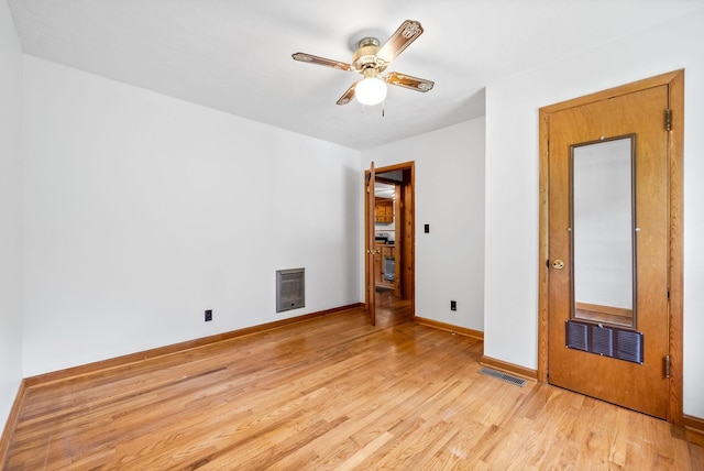 spare room with light wood-type flooring, a ceiling fan, and baseboards