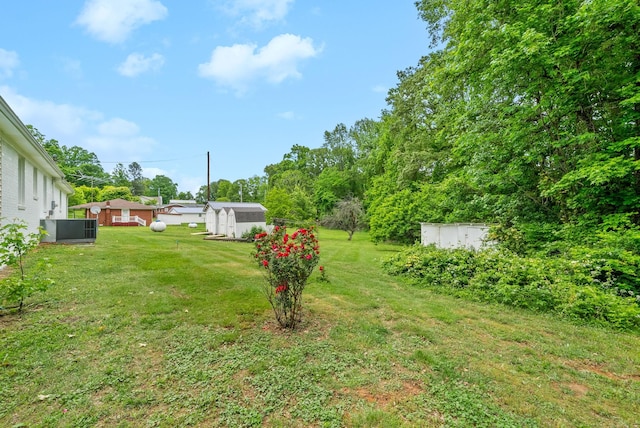 view of grassy yard featuring an outbuilding, cooling unit, and a storage unit