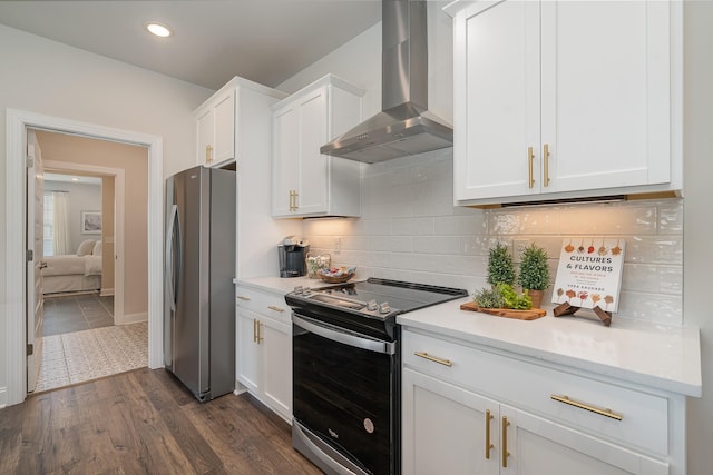 kitchen with stainless steel appliances, wall chimney range hood, white cabinets, light countertops, and decorative backsplash