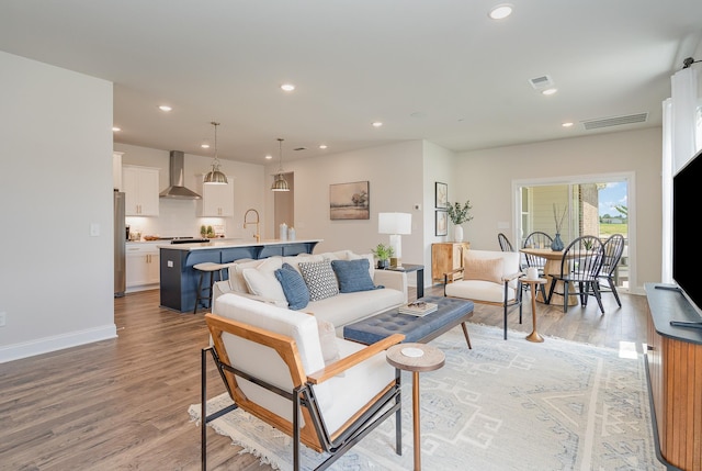 living room with light wood-style floors, recessed lighting, and baseboards