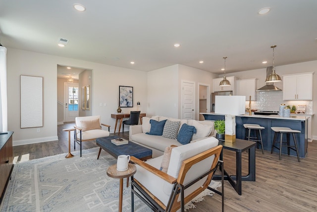living room featuring light wood finished floors, recessed lighting, and baseboards