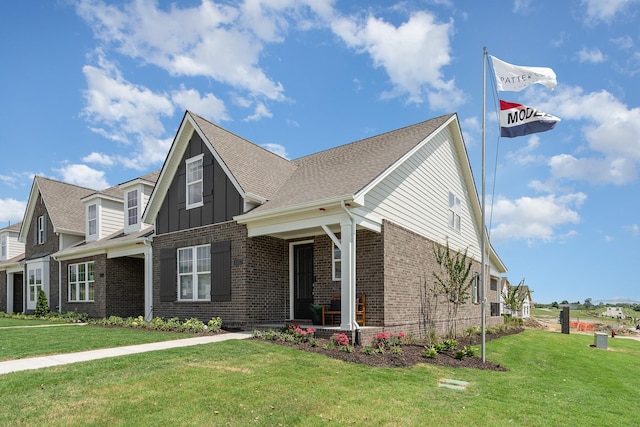 view of front of property featuring brick siding, a front yard, board and batten siding, and roof with shingles