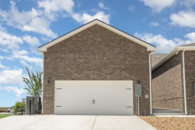 view of side of home with central AC, brick siding, driveway, and a garage