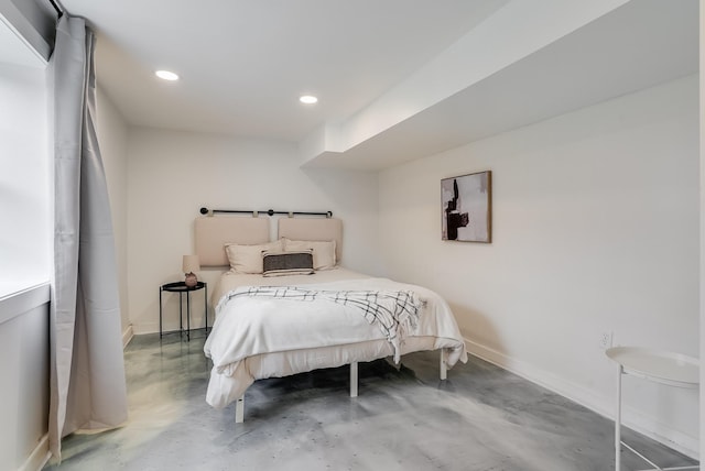bedroom with finished concrete floors, baseboards, and recessed lighting