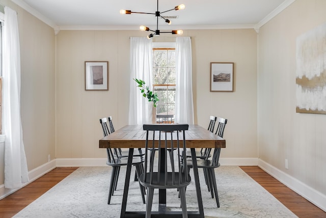 dining room with ornamental molding, wood finished floors, a chandelier, and baseboards