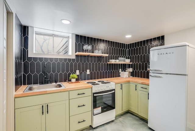 kitchen with white appliances, green cabinets, a sink, wood counters, and finished concrete floors