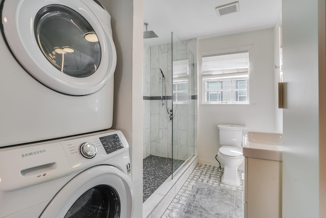full bathroom featuring stacked washing machine and dryer, a shower stall, toilet, and tile patterned flooring