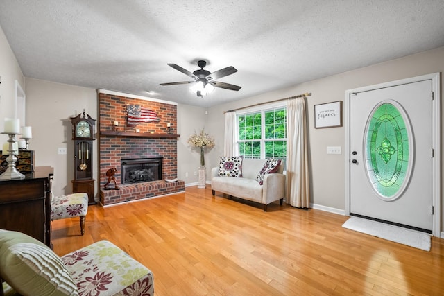 5643 Bethlehem Rd, Springfield, TN 37172 - living area featuring light wood finished floors, a ceiling fan, a textured ceiling, a brick fireplace, and baseboards