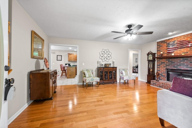 5643 Bethlehem Rd, Springfield, TN 37172 - living room with light wood-style flooring, a fireplace, a ceiling fan, baseboards, and a textured ceiling