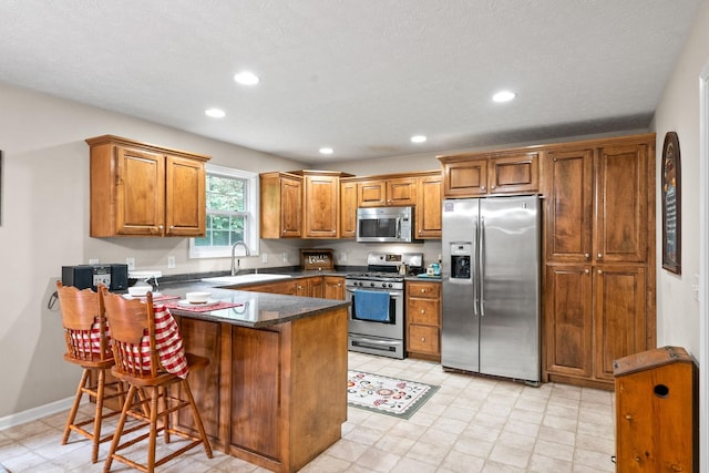 5643 Bethlehem Rd, Springfield, TN 37172 - kitchen with appliances with stainless steel finishes, a sink, a peninsula, brown cabinetry, and recessed lighting