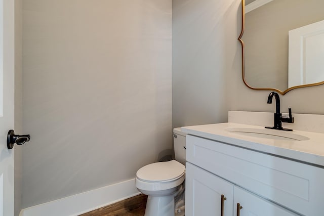 half bathroom with vanity, toilet, and wood finished floors