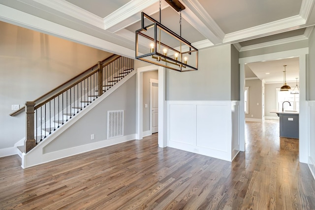 interior space featuring crown molding, stairway, wood finished floors, a chandelier, and wainscoting