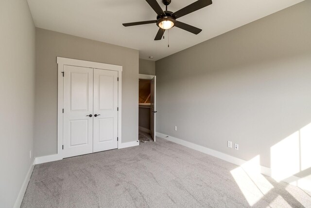 unfurnished bedroom featuring carpet floors, baseboards, a closet, and ceiling fan