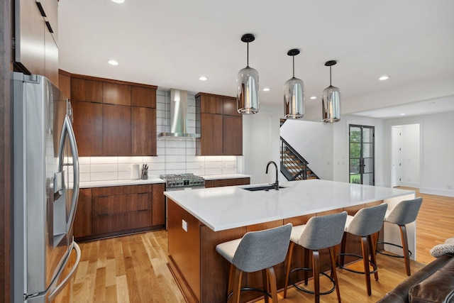 kitchen with appliances with stainless steel finishes, wall chimney exhaust hood, modern cabinets, a sink, and decorative backsplash