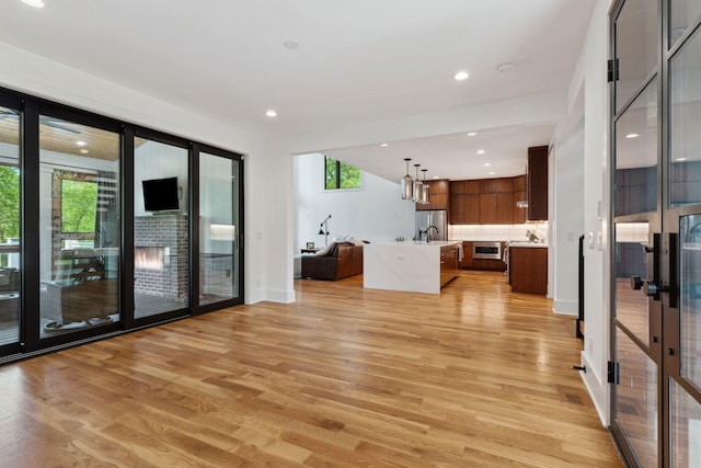 unfurnished living room with plenty of natural light, light wood-style flooring, recessed lighting, french doors, and baseboards