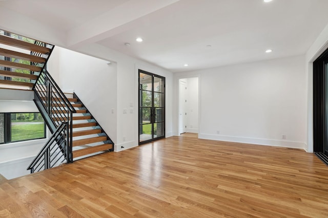 empty room featuring light wood finished floors, recessed lighting, stairway, and baseboards
