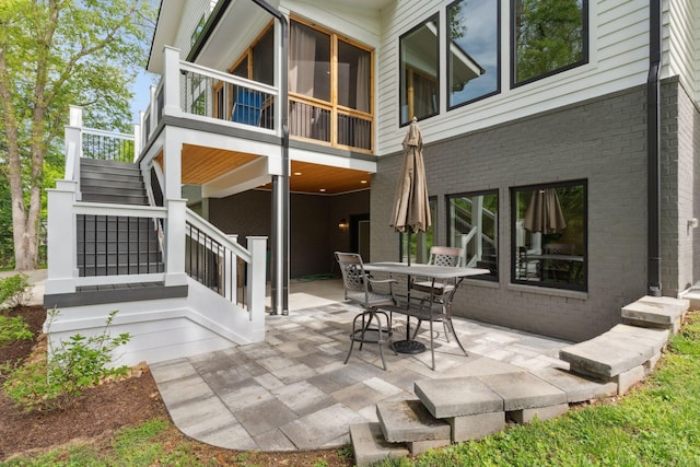 rear view of property with stairway, a patio area, brick siding, and outdoor dining area
