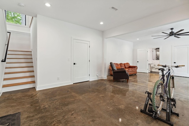 sitting room with finished concrete flooring, stairs, recessed lighting, baseboards, and a ceiling fan