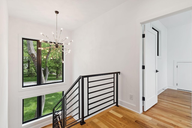 corridor featuring a chandelier, wood finished floors, and baseboards