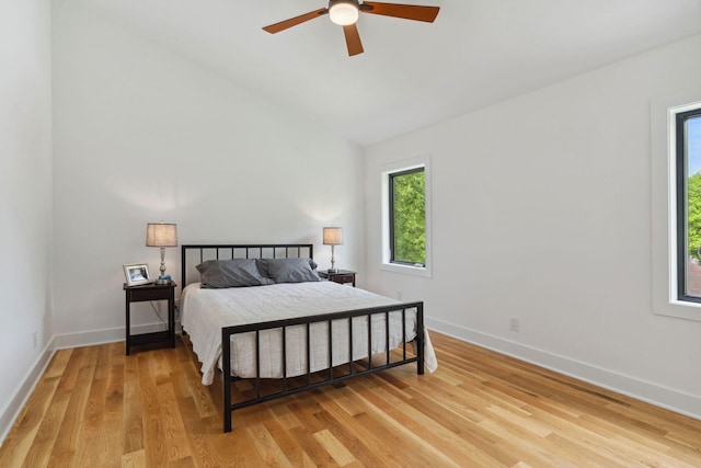 bedroom featuring light wood-style flooring, baseboards, vaulted ceiling, and ceiling fan